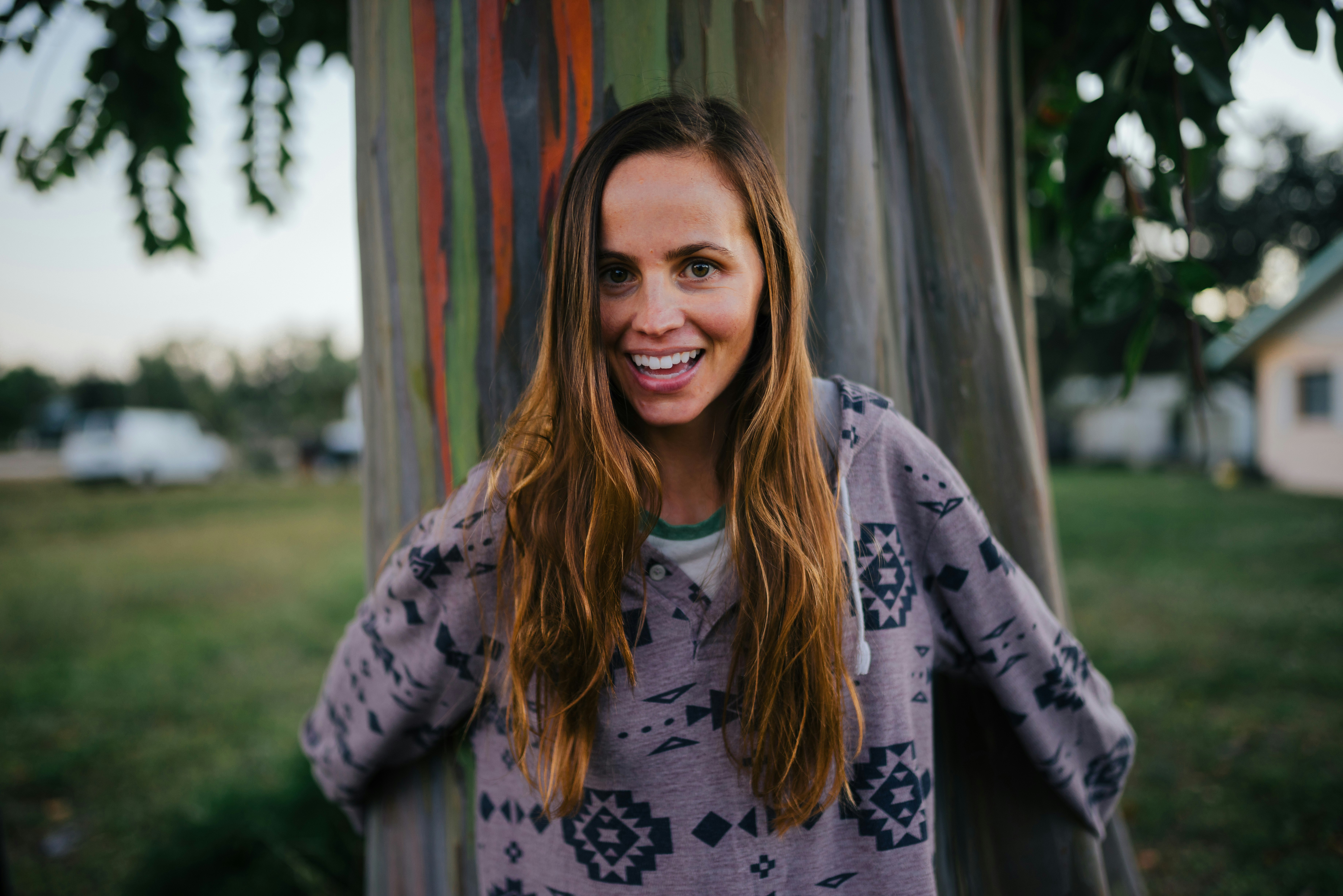 smiling holding and standing in front of tree during daytime